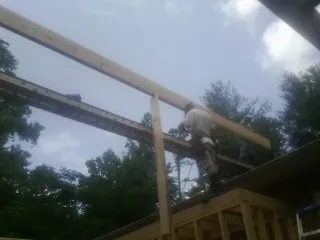 Carpenter setting a ridge beam over a new addition frame — Ice Dam Removal by Roofing Brothers in Churchville